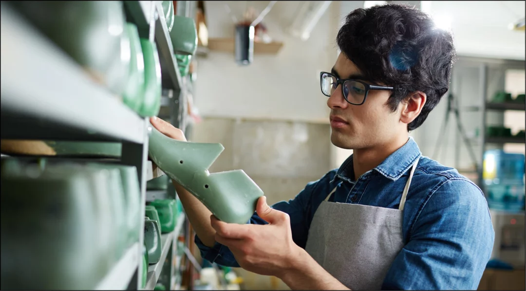 Man in glasses selects shoe mold from shelf