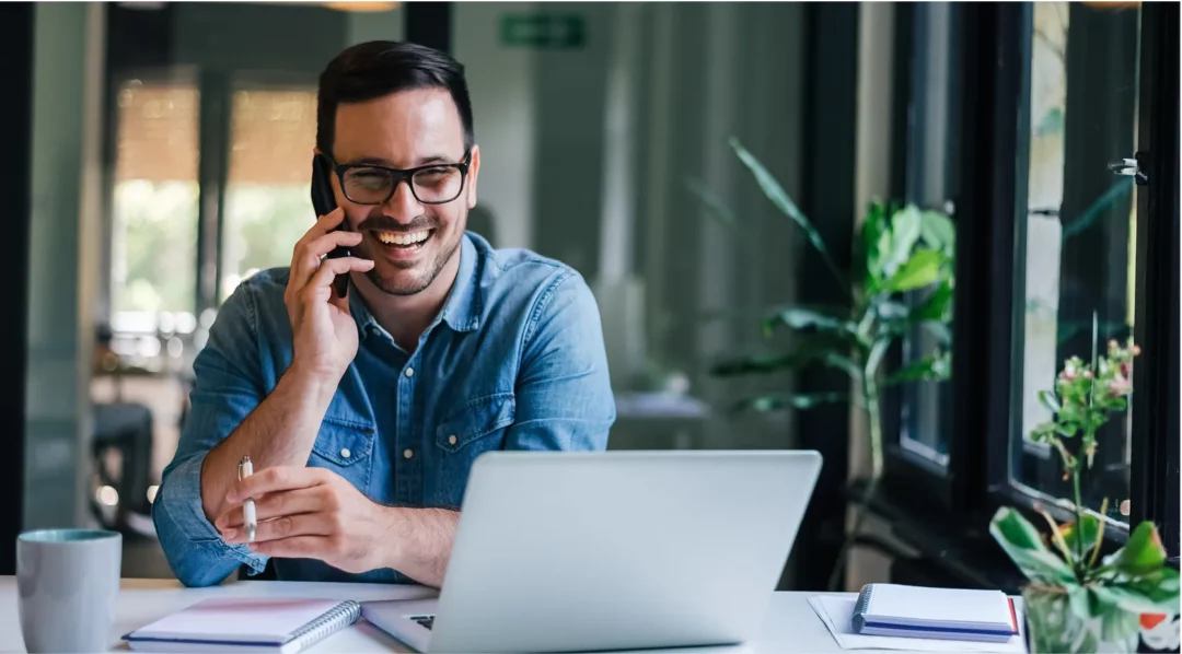 Man on phone at desk with laptop, discussing digital quality management.