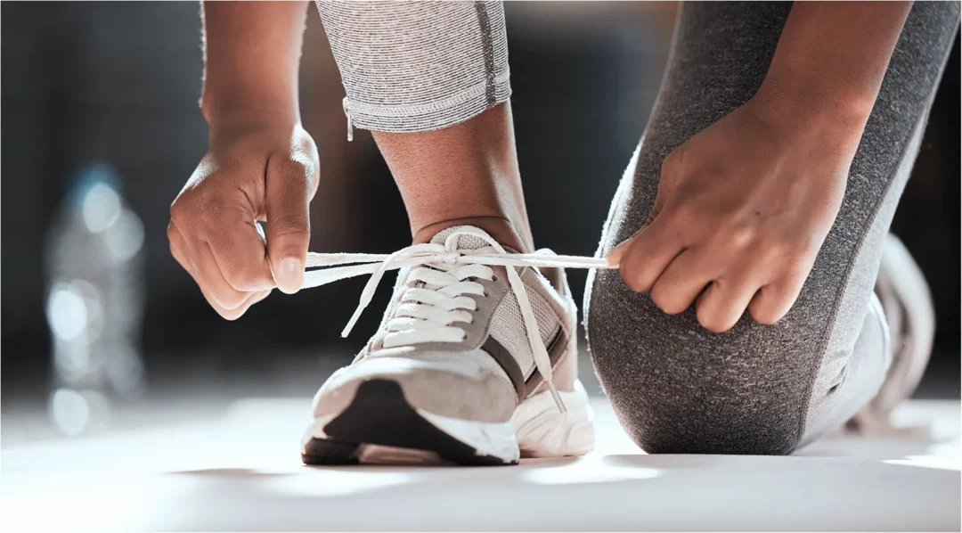 Person tying athletic shoe laces, preparing for a run.