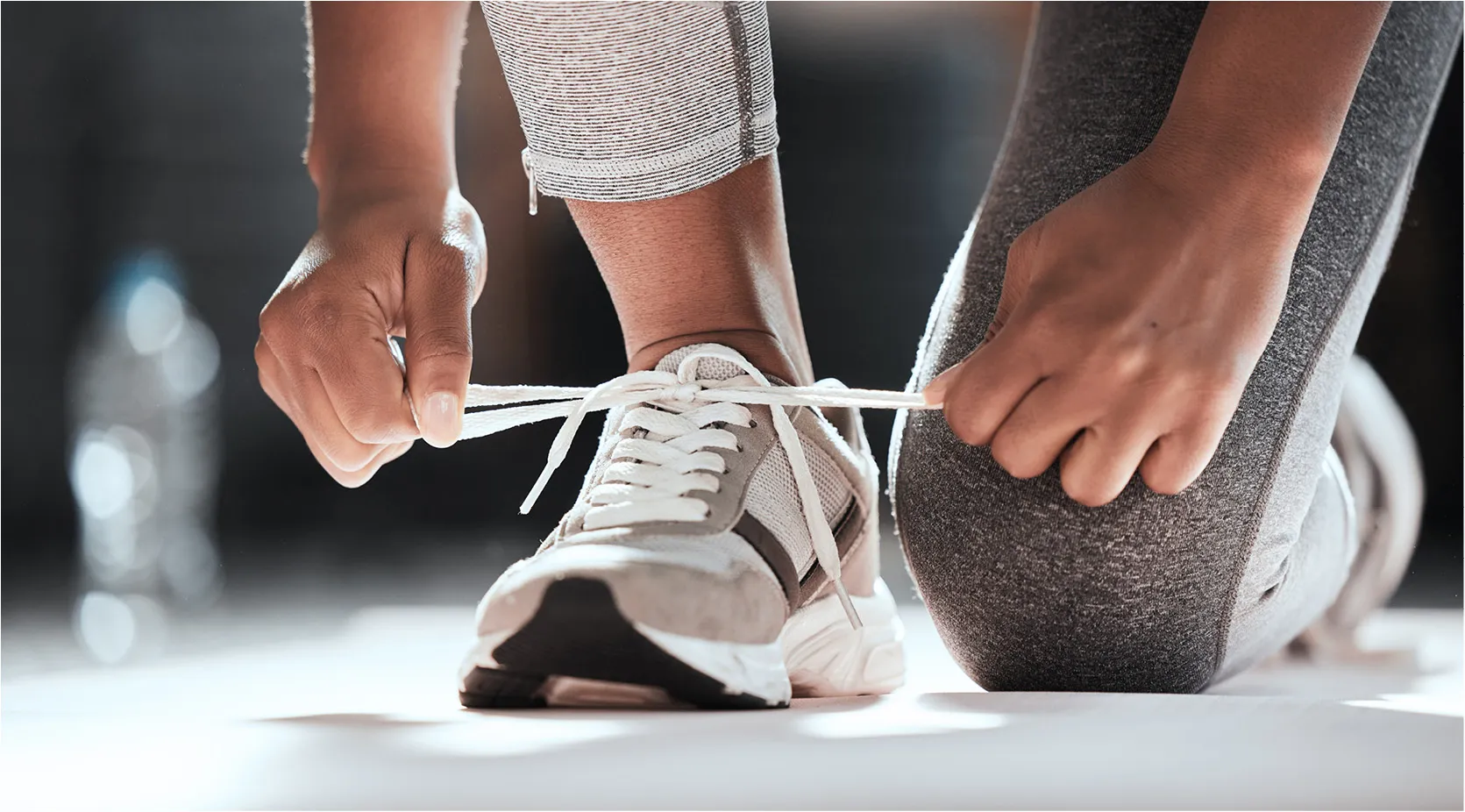 Person tying athletic shoe laces, preparing for a run.