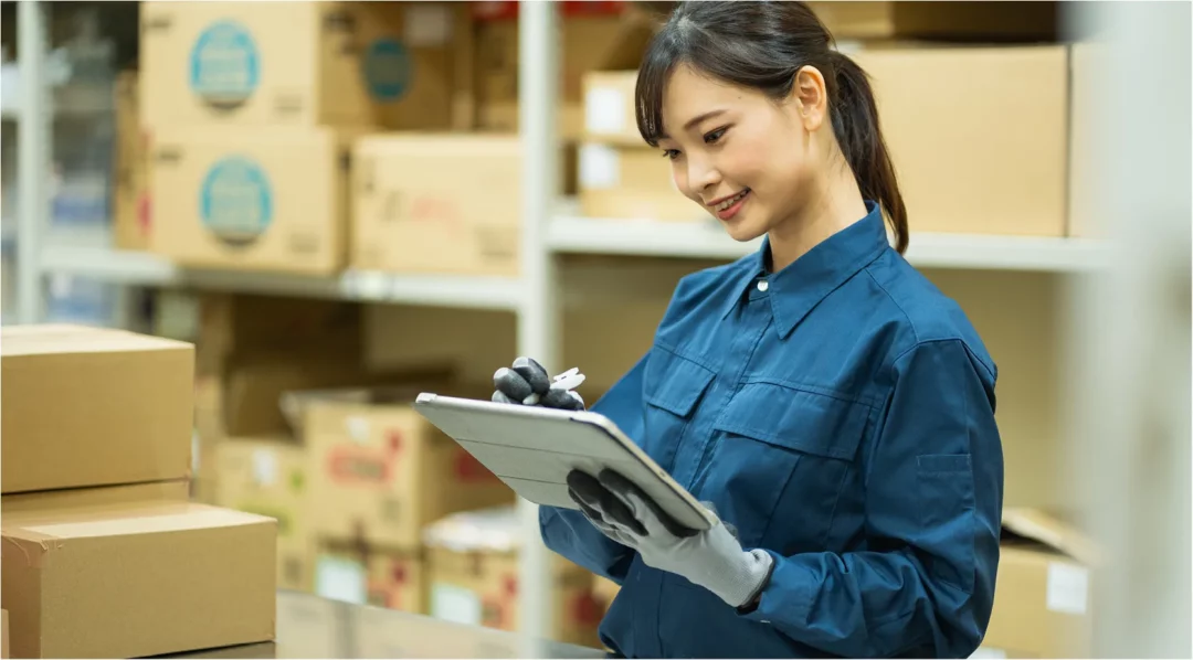 Woman in blue uniform using tablet for production tracking in warehouse