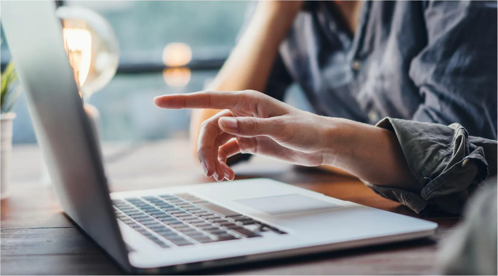 Person's hand pointing at a laptop screen, illustrating production tracking software investment.