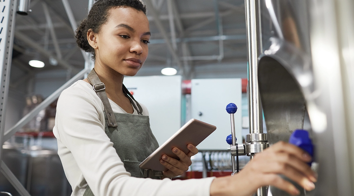 Woman uses tablet to monitor quality management system in a brewery.