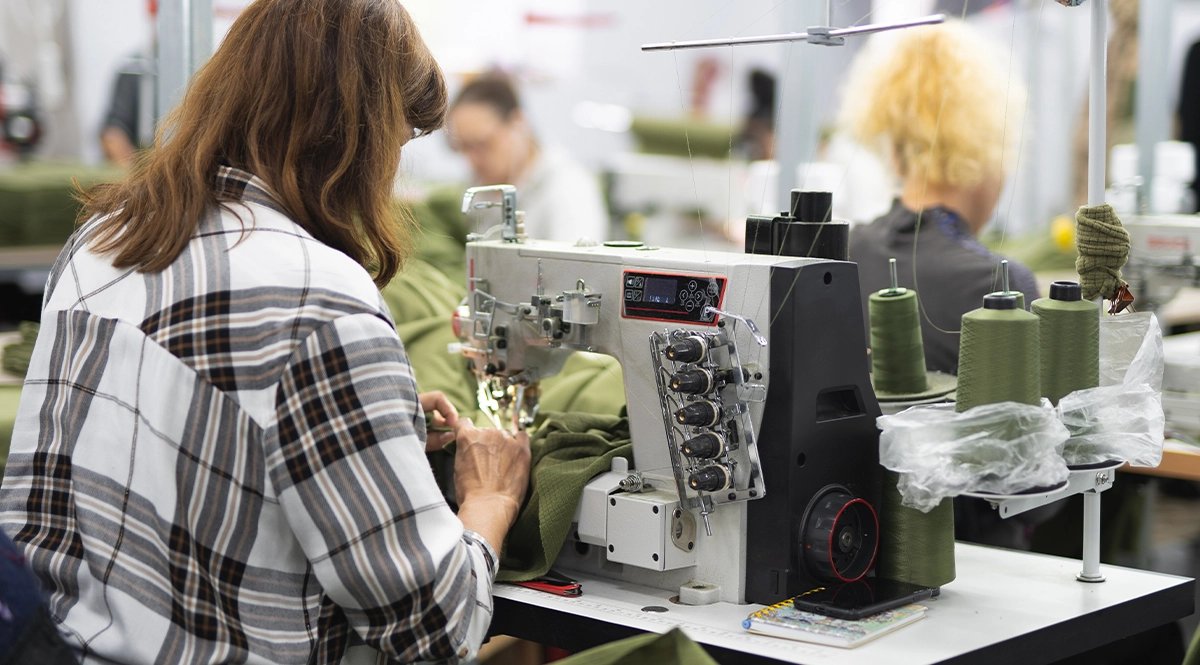 Woman sewing in a factory, highlighting ethical supply chain practices.