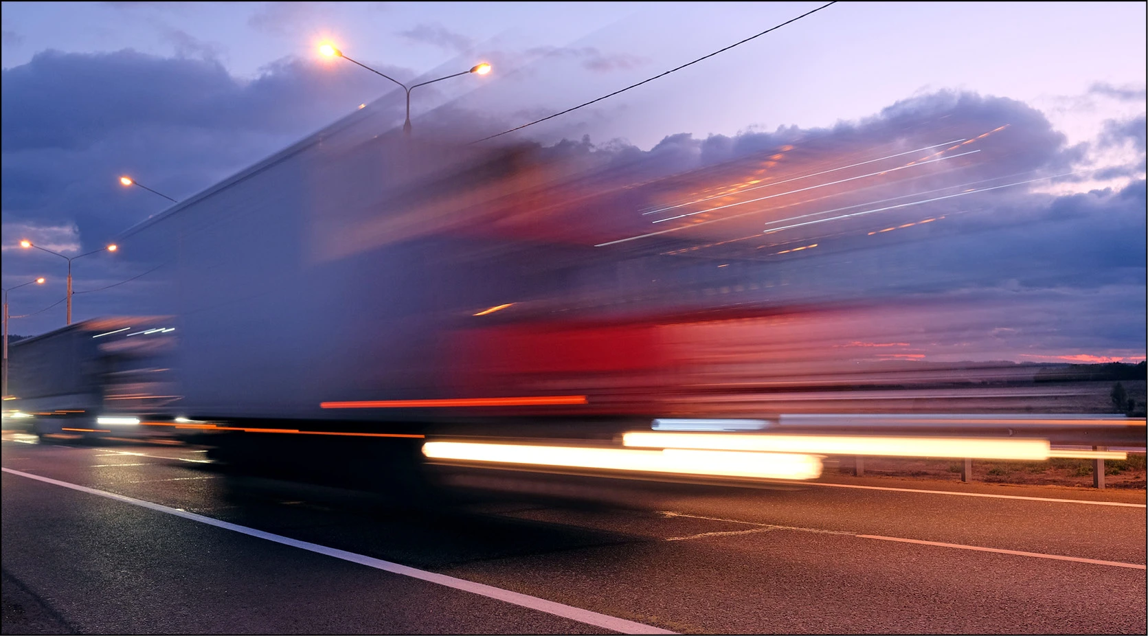 Blurred truck on highway at dusk, representing supply chain challenges