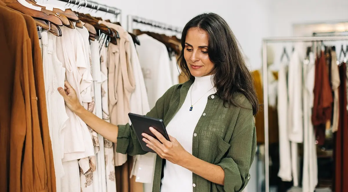 Retail manager uses tablet to check inventory in a clothing store