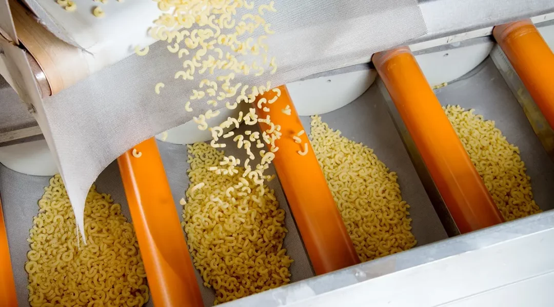 AI-powered automation in a pasta factory, with macaroni falling onto conveyor belts.
