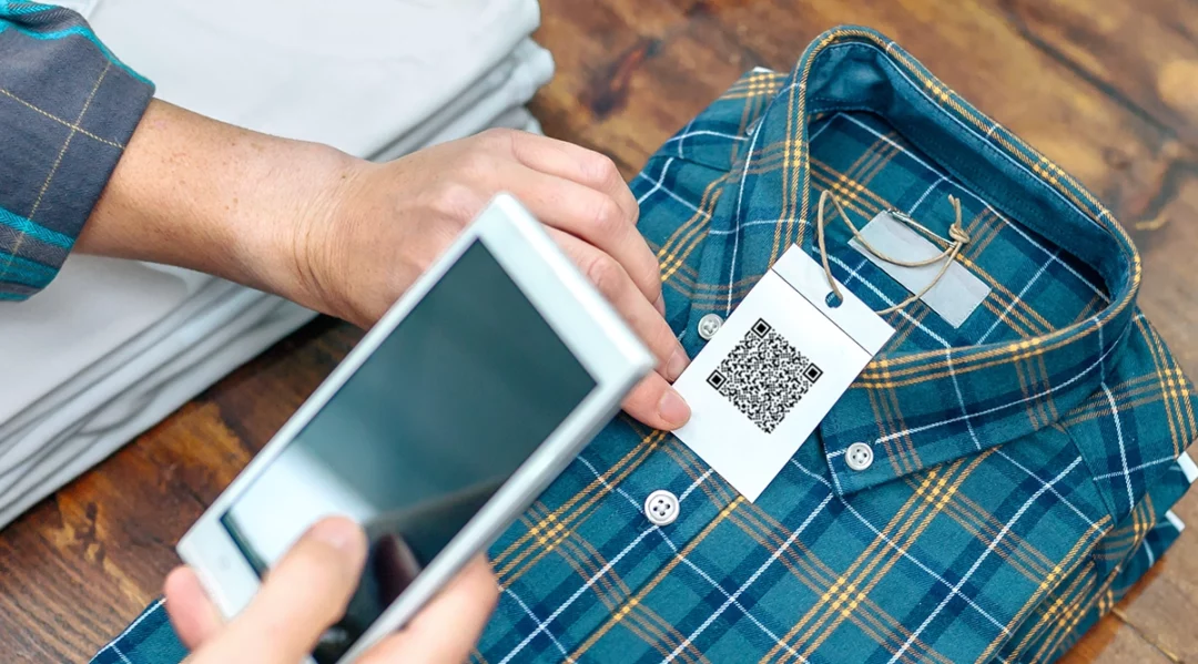 Scanning QR code on a shirt tag for EU Digital Product Passport information.