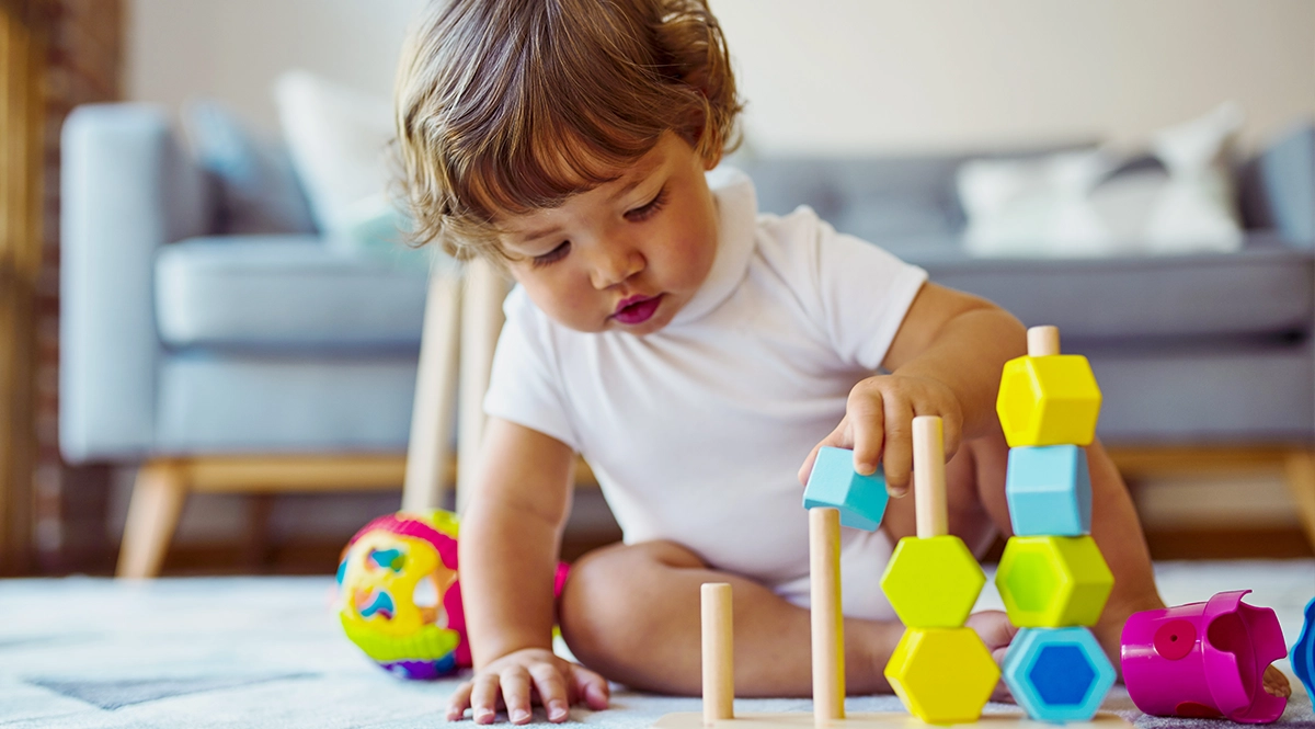 Baby playing with colorful stacking toy, highlighting early childhood development.