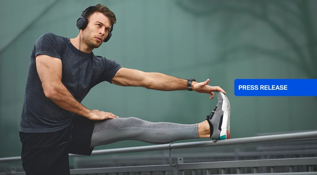 Man in headphones stretching legs outdoors, with "PRESS RELEASE" overlay.