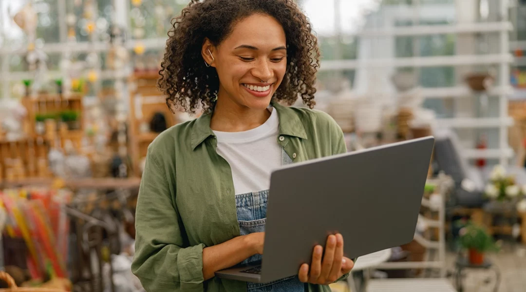 Woman using laptop in a hard goods store, discussing supply chain collaboration.