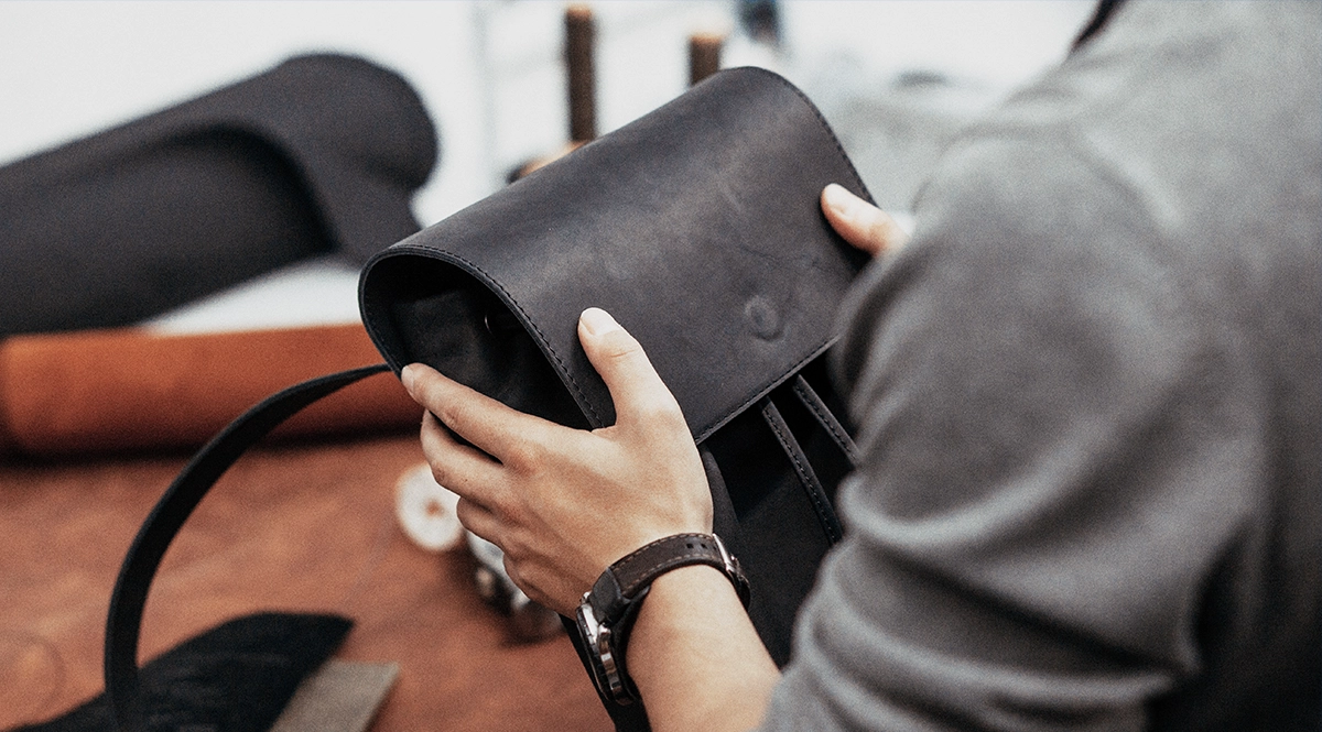 Hands crafting a black leather bag, a close-up of artisanal leatherwork.