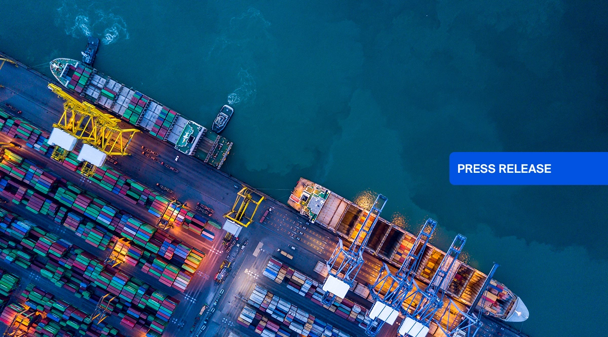 Aerial view of a busy shipping port with cargo ships and containers, with "PRESS RELEASE" overlay.