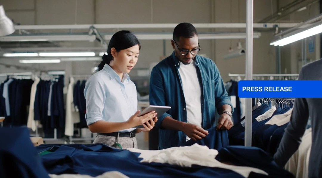 Two people in a garment factory review fabric, with "PRESS RELEASE" overlay.