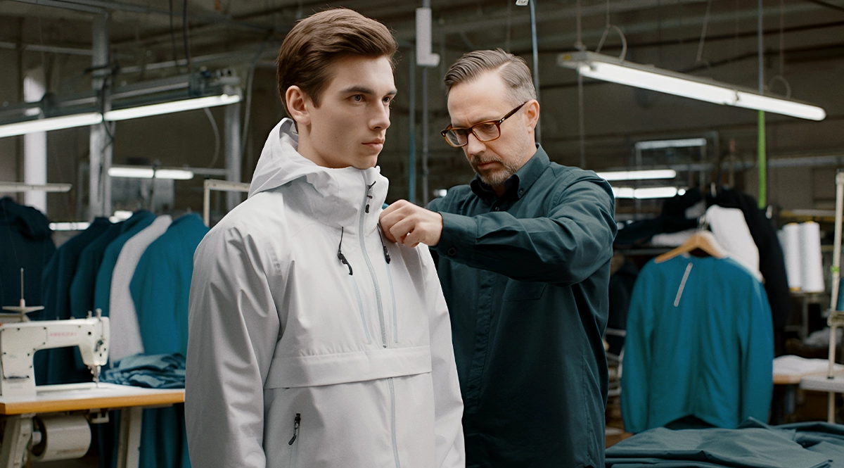 Tailor fitting a high-quality jacket on a model in a garment factory
