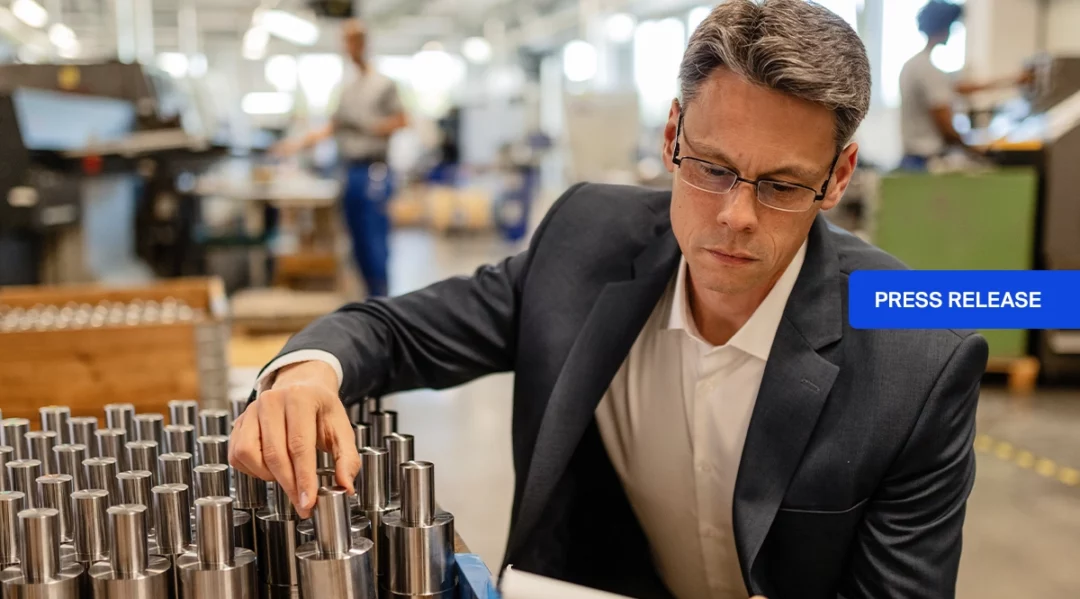 Man in suit inspecting metal parts, with "PRESS RELEASE" overlay.