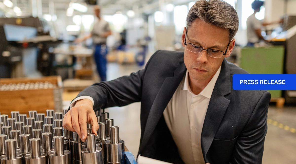 Man in suit inspecting metal parts, with "PRESS RELEASE" overlay.