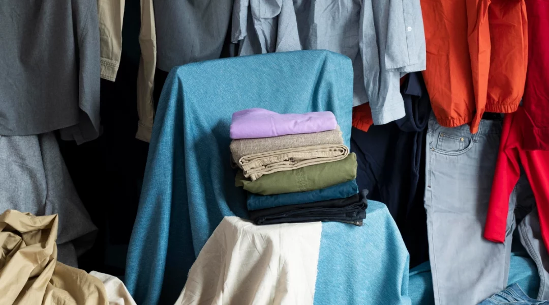 Stack of folded clothes in muted tones on blue fabric, symbolizing unsold items.